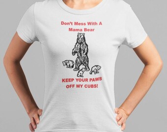 Puede incluir: Camiseta blanca con una ilustración en blanco y negro de una osa y sus cachorros. El texto "Don't Mess With A Mama Bear" y "Keep Your Paws Off My Cubs!" está impreso en rojo.