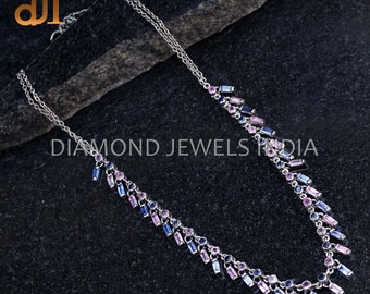May include: A silver chain necklace with a double strand design. The necklace is adorned with small blue and pink gemstones in a cascading pattern. The necklace is on a dark gray textured surface. DIAMOND JEWELS INDIA is printed on the surface.