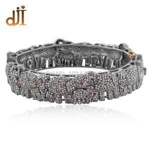 Puede incluir: Un brazalete de plata con un diseño de elefantes incrustados con pequeños diamantes y piedras preciosas rojas. El brazalete está grabado con las palabras "DIAMOND JEWELS INDIA".