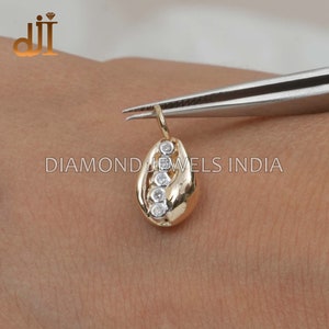May include: A gold pendant shaped like a seashell with five clear round diamonds set in a row.