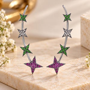 May include: A pair of silver-toned ear climbers featuring a curved bar design adorned with four star-shaped motifs. Each star is encrusted with small pavé stones in alternating colors of vibrant green, clear white, and deep magenta pink.