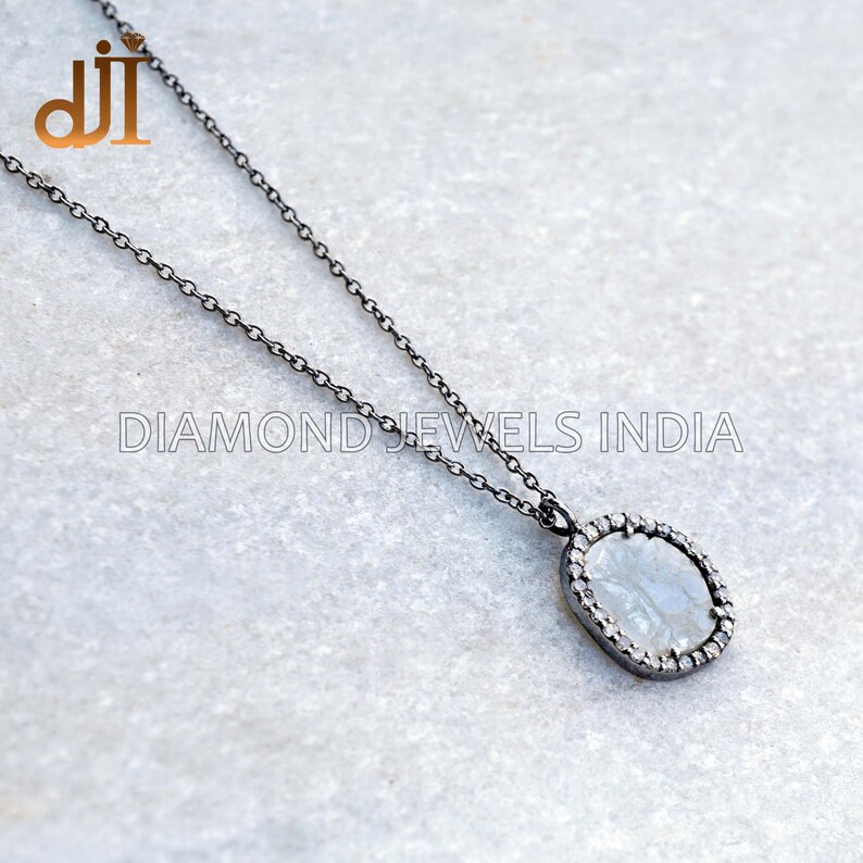 May include: A silver chain necklace with a black rhodium finish. The pendant features a rough, white diamond surrounded by a halo of smaller diamonds.