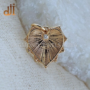 以下が含まれることがあります： 中央に小さなダイヤモンドが埋め込まれた、ゴールドのハート型のペンダント。ペンダントは、テクスチャ加工されたサンバーストデザインです。