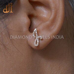 May include: A pair of diamond earrings in a delicate, curved design. The earrings are set in gold and feature a row of small diamonds.