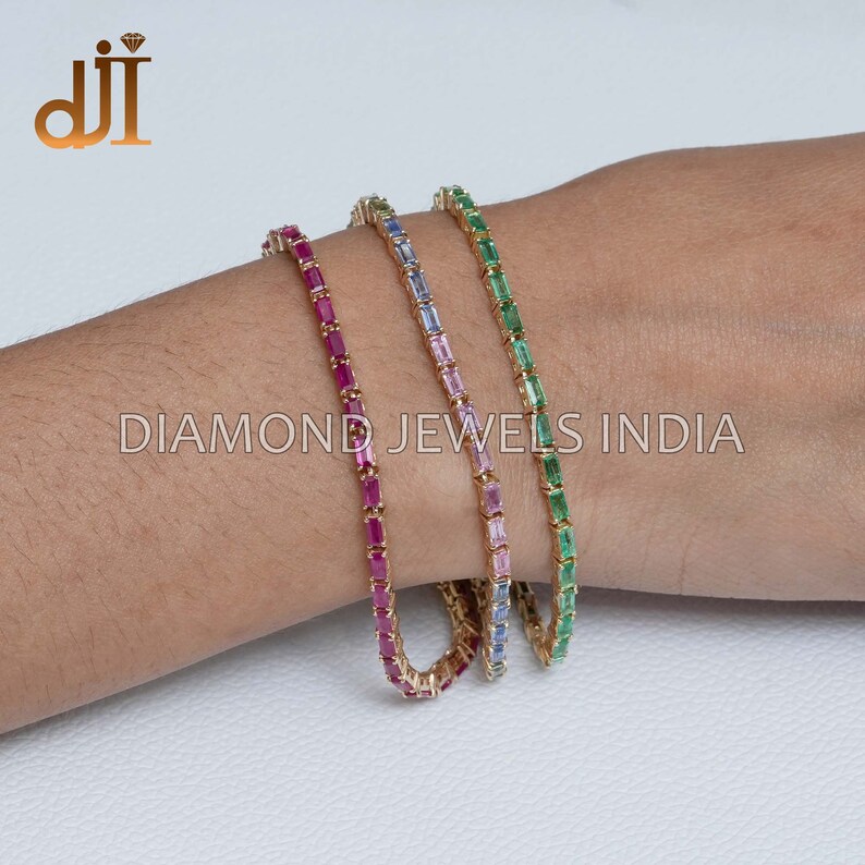 May include: Three gold bracelets with different colored gemstones. The bracelets are made of small, rectangular gemstones set in gold. The gemstones are red, blue, and green.