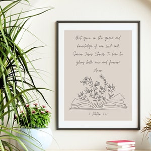 May include: A framed print with a beige background featuring a black and white illustration of an open book with flowers growing from it. The text reads "But grow in the grace and knowledge of our Lord and Savior Jesus Christ. To him be glory both now and forever! Amen. 2 Peter 3:18."