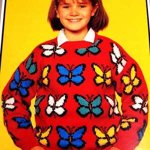 May include: A red sweater with a colorful butterfly pattern. The butterflies are in shades of blue, yellow, green, and white.