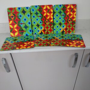 May include: Set of six colorful placemats with a geometric pattern in shades of red, green, yellow, and blue. The placemats are made of a durable material and are perfect for adding a touch of style to any dining table.