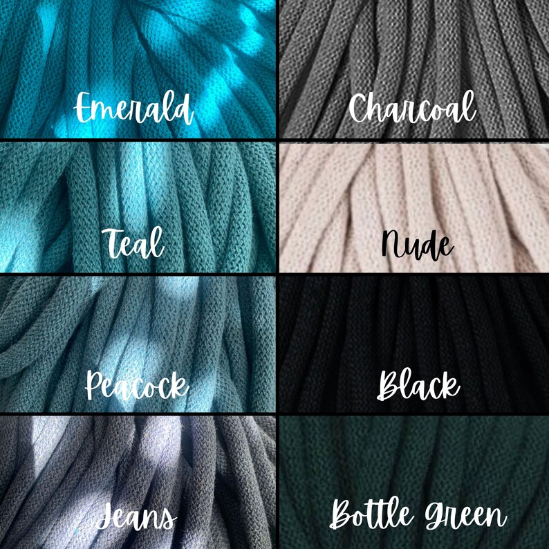 Op de afbeelding: Close-up van acht secties dik, gebreid garen in verschillende kleuren. De kleuren zijn smaragd, houtskool, teal, nude, pauw, zwart, jeans en flessegroen. Elke sectie heeft een handgeschreven label met de kleurnaam.
