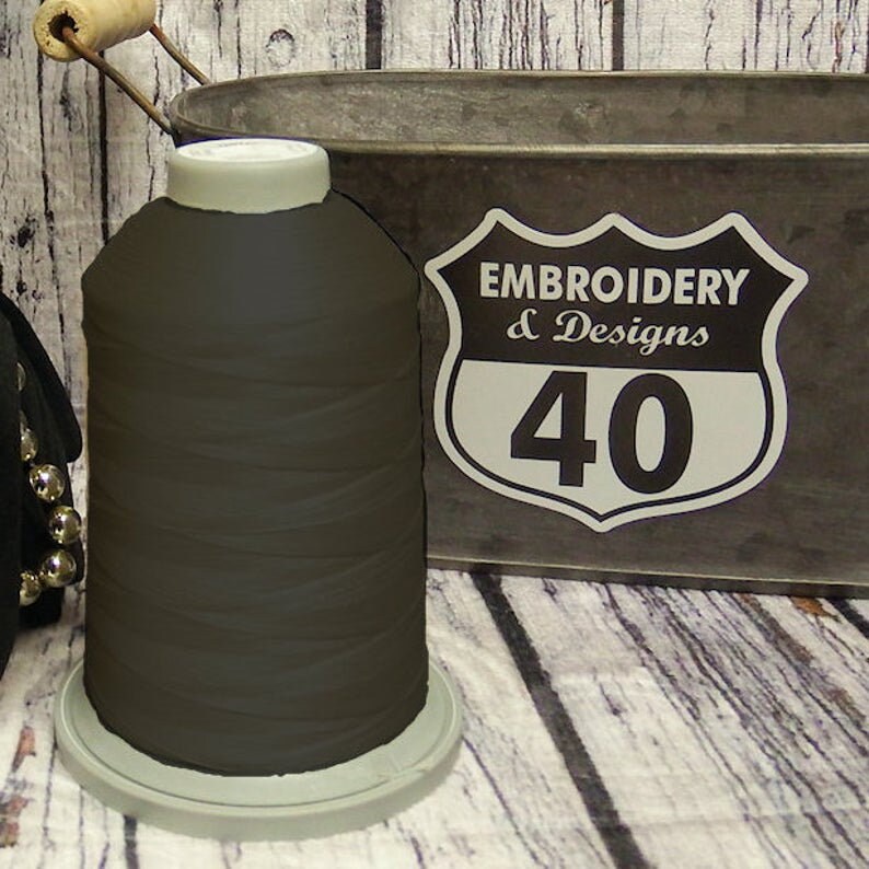 Op de afbeelding: Een spoel donkerbruin borduurgaren met een wit label met de tekst "Embroidery & Designs 40".