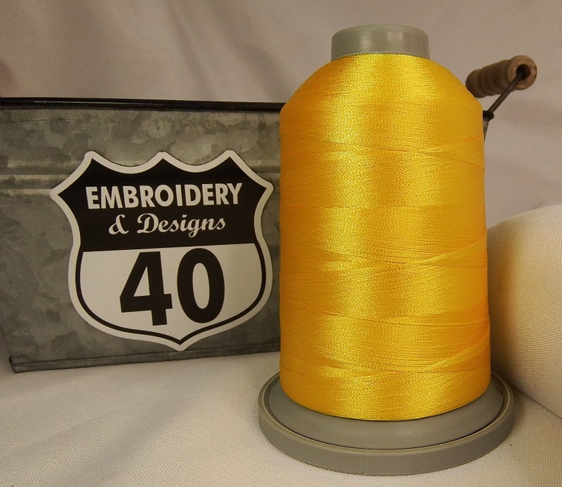 Op de afbeelding: Een spoel met felgele borduurgaren met een label met de tekst "Embroidery & Designs 40".