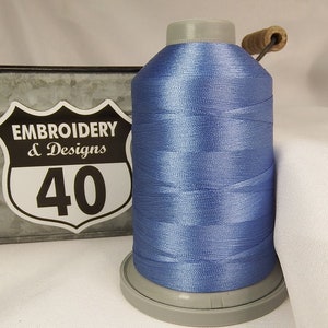 Op de afbeelding: Een spoel lichtblauw borduurgaren met een wit label met de tekst "Embroidery & Designs 40".