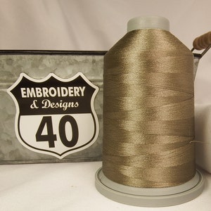 May include: A spool of brown embroidery thread with a white label that says "Embroidery & Designs 40".