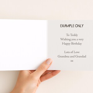 A hand holding a blank greeting card with a message for Teddy.