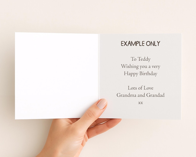 A hand holding a blank greeting card with a message for Teddy.