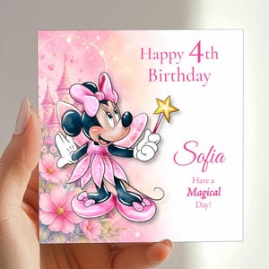 A hand holding a birthday card with a Minnie Mouse character and a pink background with flowers.