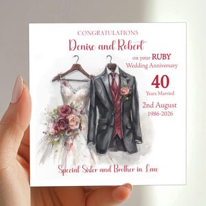 May include: A square greeting card featuring a watercolour illustration of a white wedding dress and a dark grey suit jacket with a red waistcoat and tie. Text reads: CONGRATULATIONS Denise and Robert on your RUBY Wedding Anniversary 40 Years Married 2nd August 1986-2026 Special Sister and Brother in Law.