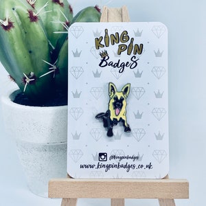 May include: Yellow and black enamel pin of a German Shepherd dog on a white card with the text "King Pin Badges" and the website address "www.kingpinbadges.co.uk".