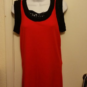 May include: A red sleeveless top with black crochet trim around the neckline and shoulders.