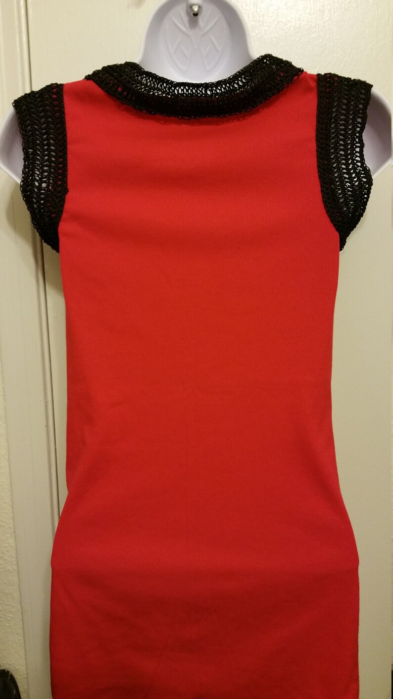 May include: A red sleeveless top with black crochet trim around the neckline and on the sleeves.