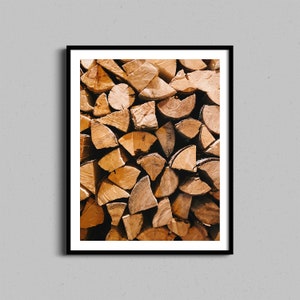 Op de afbeelding: Een close-up afbeelding van een stapel brandhout. De houtblokken zijn in een willekeurig patroon gerangschikt en zijn in verschillende tinten bruin en beige.