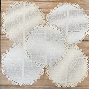 May include: Delicate, white, lace doilies with intricate floral patterns are arranged on a wooden surface. The doilies, with their detailed cut-out designs, add a touch of vintage charm to the scene.