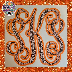 May include: Orange vinyl decal with a leopard print pattern in the shape of the letter K. The decal is on a white background.