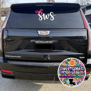 May include: Black SUV with a white "SWS" monogram with a pink bow on the back window. A colorful round sticker with the text "Sweetcream Monograms Shreveport, Louisiana" is on the rear bumper.
