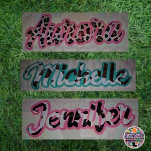 May include: Three personalized names, "Aurora", "Michelle", and "Jennifer", are written in a cursive font with a black and white cow print pattern. The names are on a white background with a pink or turquoise outline.