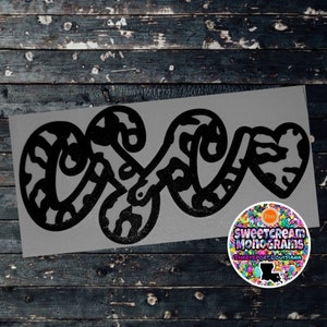 May include: Black and white patterned vinyl decal of the word "Love" with a heart shape in the "O". The decal is on a gray background. The decal is from Sweetcream Monograms, Shreveport, Louisiana.