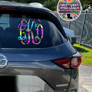 May include: A black car with a colorful monogram sticker on the back window. The sticker features the letters "SK" in a colorful, patterned design. The Etsy logo is visible in the upper right corner of the image.