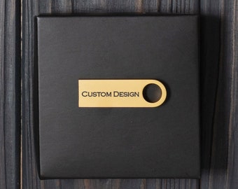 Puede incluir: Una caja negra con una etiqueta de metal dorado que dice "CUSTOM DESIGN".