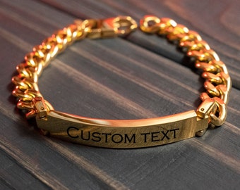 Puede incluir: Un brazalete de cadena dorada con una etiqueta rectangular que dice "CUSTOM TEXT".