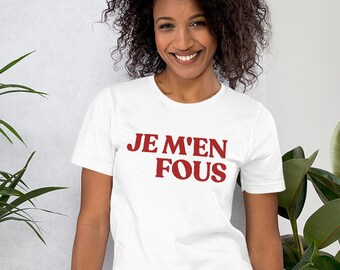 Op de afbeelding: Wit T-shirt met de tekst "JE M'EN FOU" in rood.