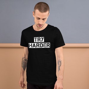 May include: Black t-shirt with white text that reads "TRY HARDER" in a distressed font.
