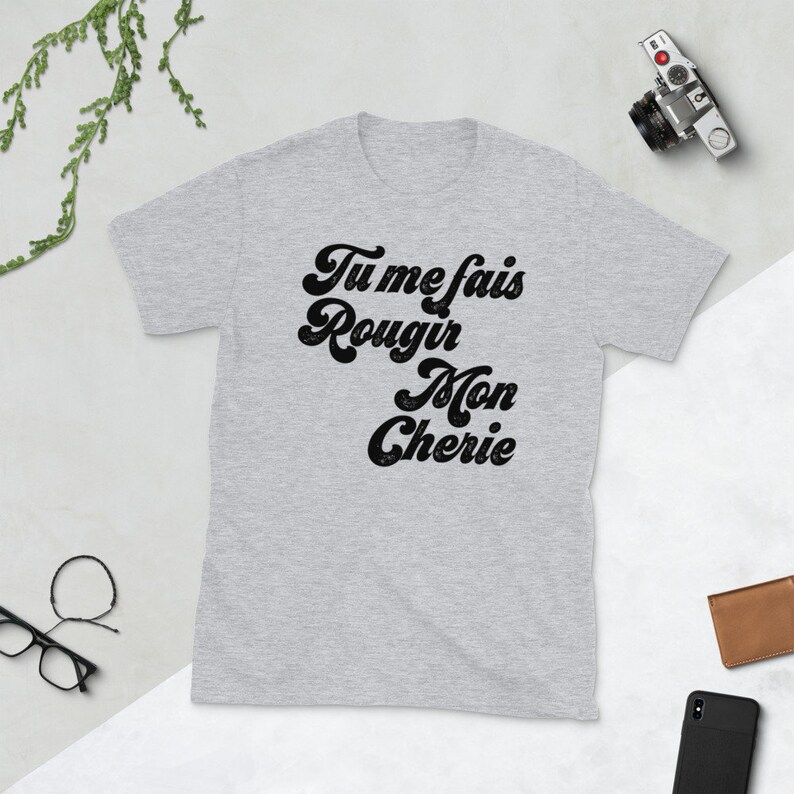 May include: Grey t-shirt with black text that reads "Tu me fais rougir Mon Cherie" in a retro font.