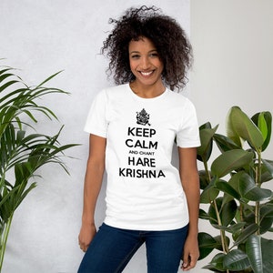 May include: White t-shirt with black text that reads "Keep Calm and Chant Hare Krishna". The text is centered on the shirt and is surrounded by a black outline. A small image of a Hindu deity is above the text.