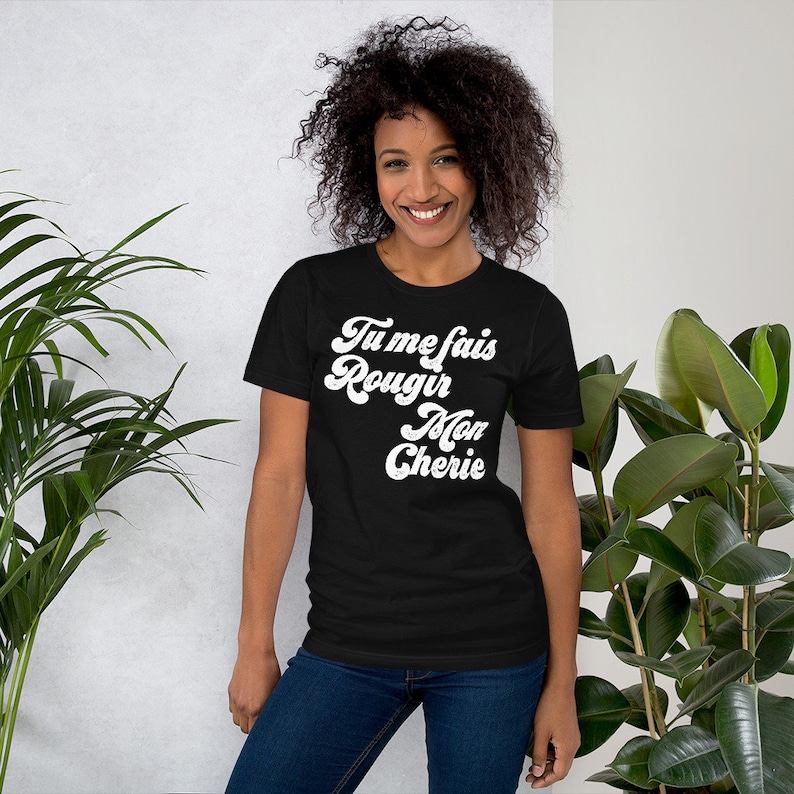 May include: A black t-shirt with white text that reads "Tu me fais rougir Mon Cherie" in a retro font.