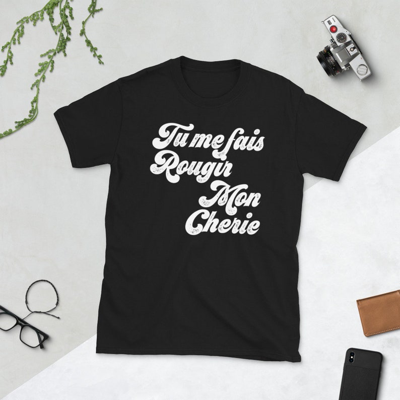 May include: Black t-shirt with white text that reads "Tu me fais rougir mon ch&eacute;rie" in a retro font.