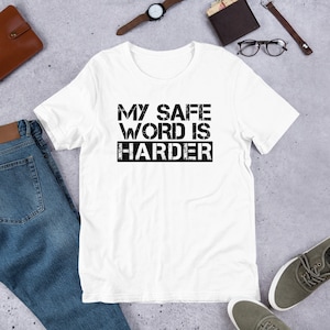 Może przedstawiać: Biała koszulka z czarnym nadrukiem "My Safe Word Is Harder".