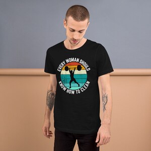 May include: Black t-shirt with a vintage-style graphic of a woman lifting weights. The graphic says "Every Woman Should Know How To Clean".