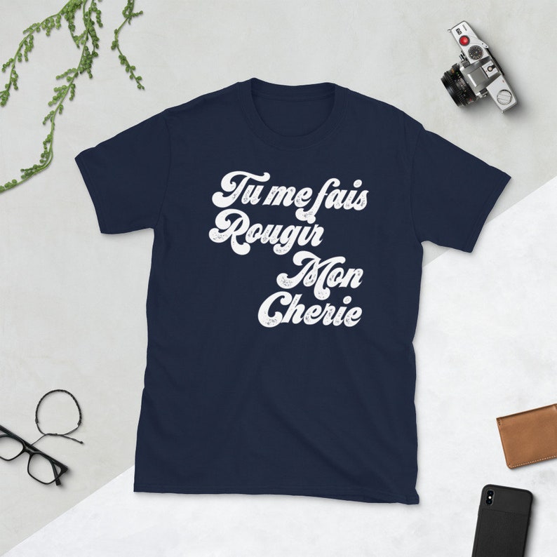 May include: Navy blue t-shirt with white text that reads "Tu me fais rougir Mon Cherie" in a retro font.