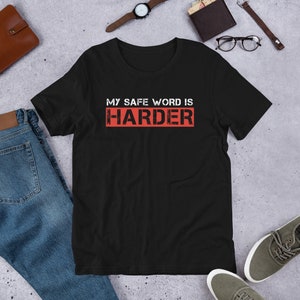 Może przedstawiać: Czarny T-shirt z napisem "My safe word is HARDER" w kolorze czerwonym.