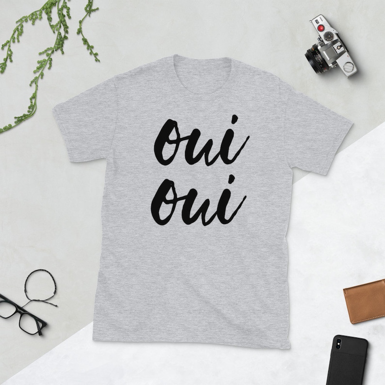 May include: A gray short-sleeved t-shirt with the text "oui oui" printed in black.