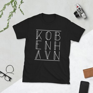 May include: Black t-shirt with a white graphic design that says "KOBENHAVN" in a unique, geometric font.