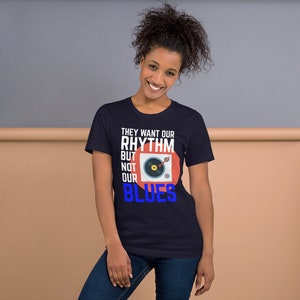 May include: A navy blue t-shirt with a white graphic of a record player and the text "They want our rhythm but not our blues".
