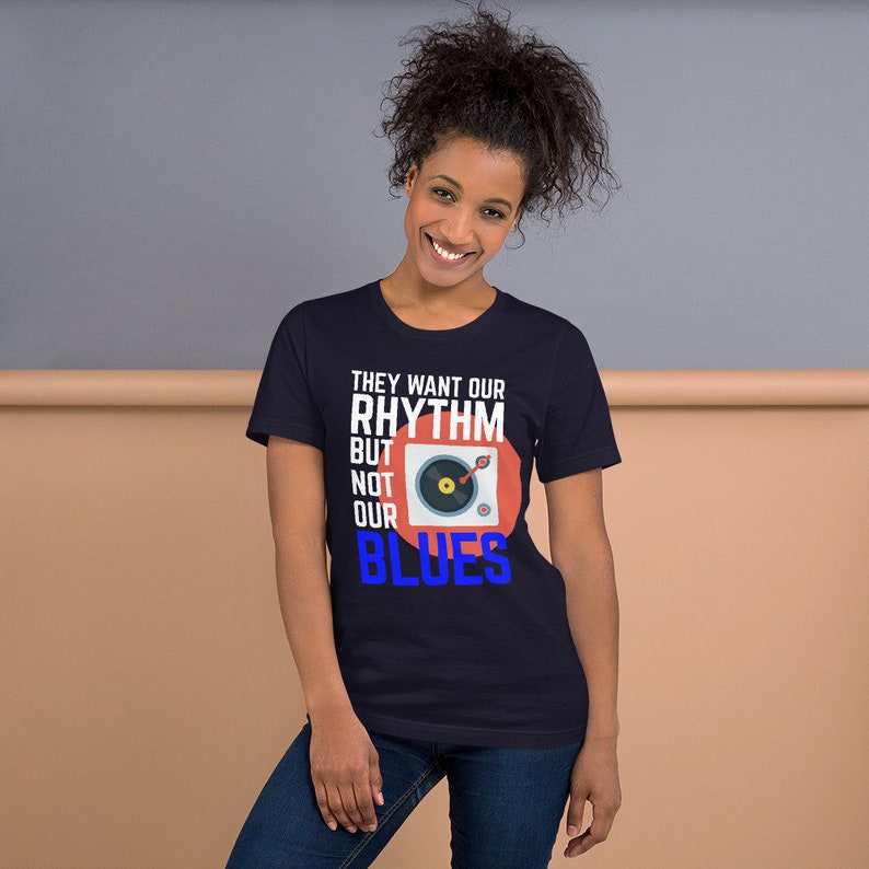 May include: A navy blue t-shirt with a white graphic of a record player and the text "They want our rhythm but not our blues".