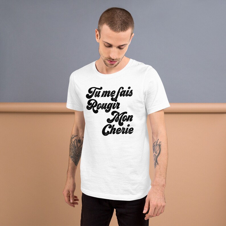 May include: White t-shirt with black text that reads "Tu me fais rougir Mon Cherie" in a retro font.