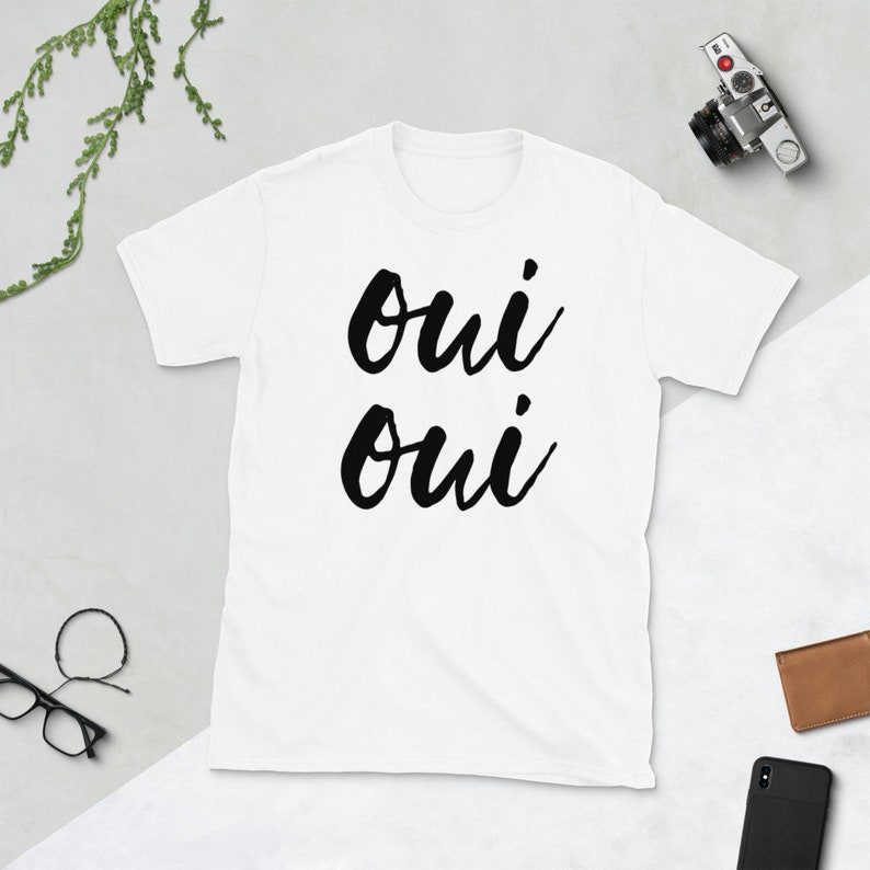 May include: White t-shirt with black text that says "oui oui" in a handwritten font.