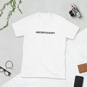 May include: White t-shirt with the text "ABCDEFUCKOFF" printed in black on the front.